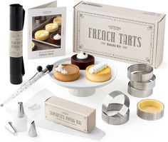 an assortment of french tarts on a plate with measuring cups and saucers next to it