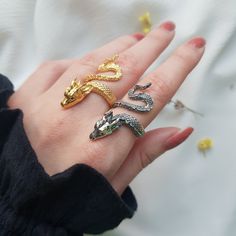 a woman's hand with three rings on it and two snakes in the middle