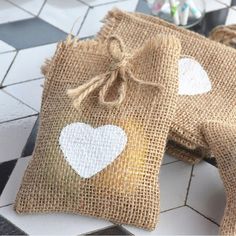 two burlap bags with hearts on them sitting on a tiled floor next to a vase