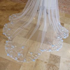 a wedding veil with blue flowers on the floor