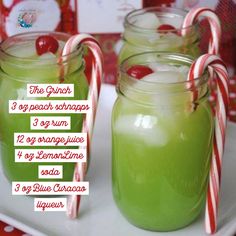 three jars filled with green liquid and candy canes on top of a white plate