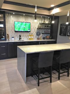 a large kitchen with an island in the middle and bar stools at the end