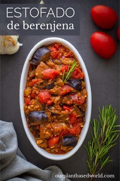 a bowl filled with stew next to tomatoes and garlic