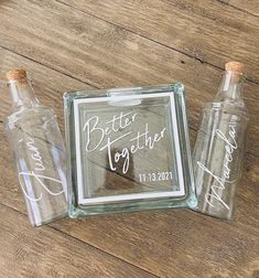 three glass bottles sitting on top of a wooden floor next to a sign that says better together