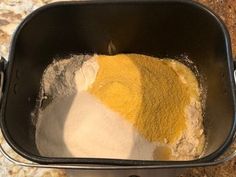 the ingredients are mixed together in a black bowl on the counter top, including yellow and white powder