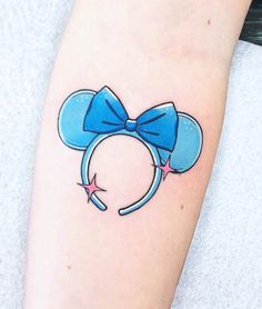 a person with a tattoo on their arm that has a blue bow and stars around it