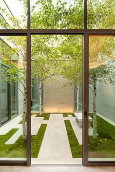 an open room with glass walls and grass on the floor, leading to a courtyard