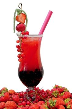 a glass filled with liquid and strawberries on top of a pile of other fruit