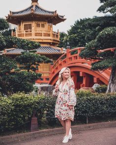 a woman standing in front of a building with a pagoda on it's roof