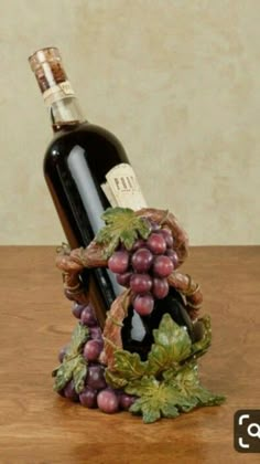 a bottle of wine sitting on top of a wooden table next to a bunch of grapes