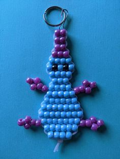 a blue and purple beaded lizard keychain on a blue background