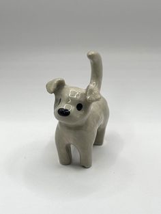 a small ceramic dog figurine on a white surface with one paw in the air