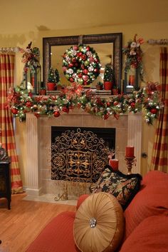 a living room decorated for christmas with red and green decorations on the fireplace mantel