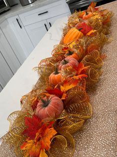 a kitchen counter topped with pumpkins and fall leaves on top of each other,