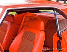 the interior of an orange sports car with matching leather upholstered seats and floor mats