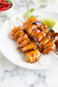 chicken skewers on a white plate with lime wedges next to the side