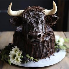 a chocolate cake decorated with an animal's head and flowers on a wooden table