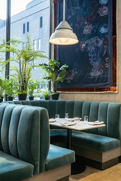 the inside of a restaurant with green velvet booths and potted plants on the tables