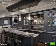 a large kitchen with marble counter tops and bar stools in front of an island