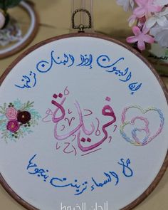 an embroidered sign with arabic writing on it and flowers in vases next to it