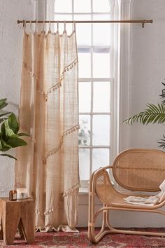 a living room with a chair, potted plant and rug on the floor in front of a window