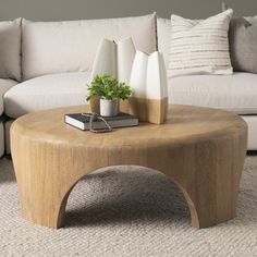 a coffee table with two vases and a book on it in front of a couch