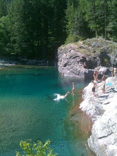 people are swimming in the water near some rocks