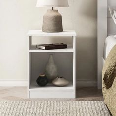 a white shelf with two vases on it next to a bed