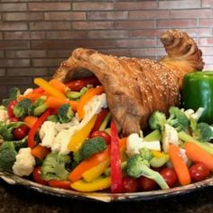 a platter filled with vegetables and meat on top of a table next to a brick wall