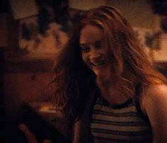 a woman with long red hair standing in a kitchen next to a stove top oven