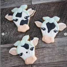 three decorated cow cookies sitting on top of a wooden table