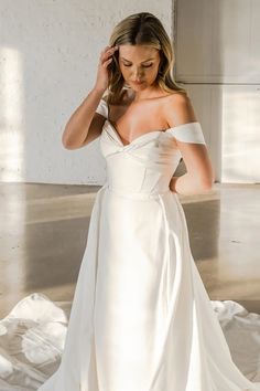 a woman in a white wedding dress is posing for the camera with her hand on her head