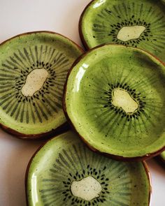 four kiwi plates with holes in them on a table