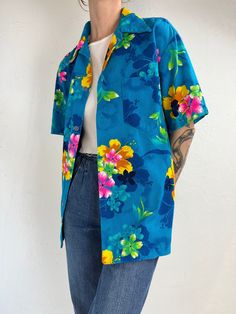 "- Vintage 1970s blue hawaiian print shirt - Feels like 100% polyester - Made in Hawaii - Tagged L Chest: 22.5\" Length: 26\"" Hawaiian Floral Print Collared Camp Shirt, Hawaiian Collared Camp Shirt With Floral Print, Blue Camp Shirt For Beach In Spring, Printed Hawaiian Button-up Shirt, Hawaiian Shirt With Floral Print And Camp Collar, Blue Button-up Hawaiian Shirt For Vacation, Summer Blue Hawaiian Shirt With Prints, Collared Hawaiian Shirt With Floral Print For Beach, Tropical Collared Hawaiian Shirt With Floral Print