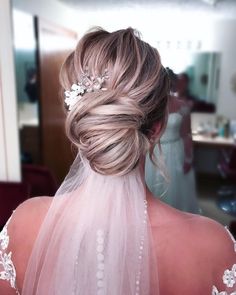 the back of a bride's head wearing a veil and flowers in her hair