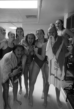 a group of young women standing next to each other in a bathroom with towels on their shoulders