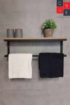 two towels are hanging on a shelf above a potted plant and toilet paper rolls