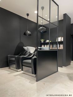 the interior of a salon with black walls and white flooring, two chairs are in front of an open glass door