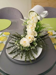 white flowers and greenery are arranged on a table