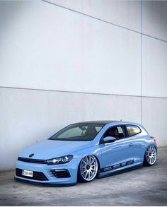 a blue car parked in front of a white wall