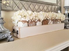 some white flowers are in small vases on a mantle