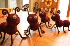 some very cute little red bugs on a wooden table in the middle of a room