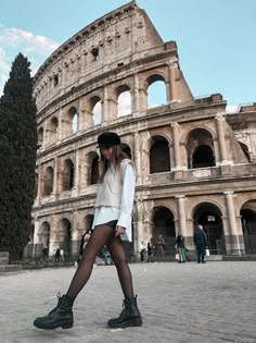 a woman is walking in front of an old building with roman ruins on the side