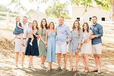 a family posing for a photo in front of a white fence with trees and grass