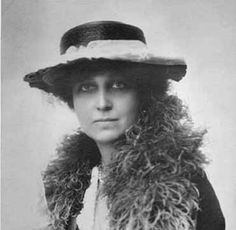 an old black and white photo of a woman wearing a hat with fur on it