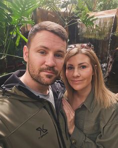 a man and woman posing for a photo in front of a waterfall