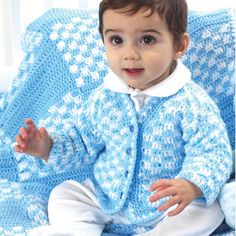 a little boy sitting on top of a couch wearing a blue crocheted sweater