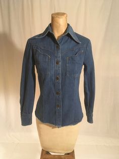 "vintage 1970s women's western denim shirt Brittania Sportswear cotton blue jean button up front 2 bust pockets long sleeve/button cuff yoke hem good vintage condition, light wear labeled size 5, very petite, see below measures, lying flat, shoulder-  13 1/2\" sleeve-20 1/2\" chest-16\" waist-14\" hem-16\" length from top at neck seam below collar-22\"" Fitted Vintage Button-up Denim Top, Fitted Denim Blue Shirt With Button Closure, Fitted Denim Blue Button-up Shirt, Classic Fitted Denim Top With Buttons, Fitted Collared Denim Jacket With Buttons, Fall Denim Tops With Snap Buttons, Fitted Blue Denim Top For Fall, Fitted Denim Blue Cotton Shirt, Fitted Collared Denim Jacket With Button Closure