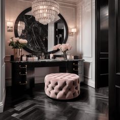 a vanity with a round mirror and pink stool in front of it, next to a chandelier