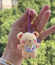 a hand holding a small crocheted teddy bear